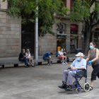Una mujer pasea a un hombre por las calles de Barcelona equipados con mascarillas.