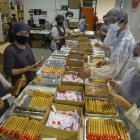 Treballadors i voluntaris de l’obrador de galetes El Rosal preparen la comanda.