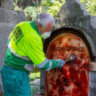 Un operari neteja la làpida tacada amb pintura roja.