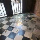 La entrada a la sede de Òmnium en Barcelona con los cristales destrozados y marcas de quemaduras.