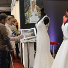 Visitants s’interessen pels catàlegs de vestits de núvia d’un dels expositors de la fira.