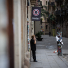 Una dona parla per telèfon en un carrer del centre de Barcelona, desert per l’ordre de confinament.
