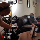 Una càmera grava l’entrevista a una persona gran, confinada.