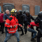 Policías nacionales cargan en un colegio electoral de Girona el 1-O en presencia de un bombero.