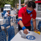 Un camarero desinfecta las mesas de la una terraza en un bar de Huelva.