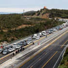 Camiones y coches bloqueados en La Jonquera, y manifestantes caminando por la vía, ayer.