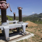 Los disyuntores procedentes de una central hidroeléctrica, con la presa de Sant Antoni al fondo.