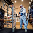 Un treballador desinfecta una llibreria a Roma, negocis que Itàlia permet reobrir ja.