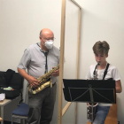 Un profesor de la Escuela Municipal de Música de Balaguer dando clases de saxo tras una mampara.