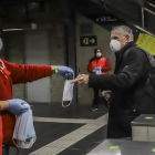 Una voluntaria de la Cruz Roja entrega una mascarilla a un pasajero, ayer, en una estación de la red de metro de Barcelona.
