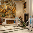 Equipos de limpieza desinfectan un altar en una iglesia en Roma.