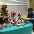 Dos bomberos juegan con dos niños del hospital Sant Joan de Déu durante la sesión de fotos. 