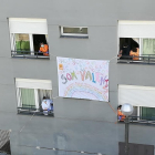 Los trabajadores de la residencia de El Pont de Suert colgando una pancarta en la fachada del edificio.