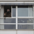 Un home amb mascareta i el polze aixecat surt a una finestra de casa seua, ahir a Madrid.