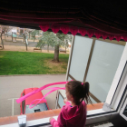 Una nena mentre balla a la finestra de casa seva.