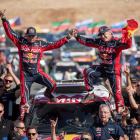 Carlos Sainz y su copiloto Lucas Cruz celebran el triunfo en el Dakar subidos a su vehículo.