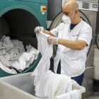 Un empleado de la lavandería del Grup Alba de Tàrrega trabajando con mascarilla y guantes.