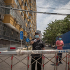 Un guàrdia de seguretat impedeix el pas a un carrer proper al mercat de Pequín infectat per Covid-19.