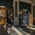 Dos treballadors recullen la terrassa d'un bar del centre de Barcelona.