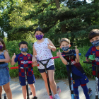 Varios niños jugando ayer con patinete por calles de Lleida llevando mascarillas infantiles