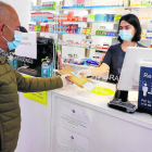 Un cliente recogiendo una mascarilla gratis con su tarjeta sanitaria en Lleida.