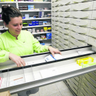 Una empleada de una farmacia en Pardinyes muestra los cajones vacíos de medicamentos.