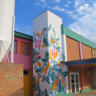 La artista Lara Costafreda pintando el exterior de la escuela.