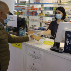 Una farmacéutica entrega una mascarilla de la Generalitat a un ciudadano el pasado lunes. 