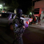 Agente armado junto a una camioneta que transporta un cadáver.