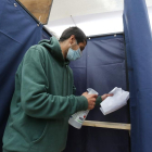 Un home desinfecta una cabina de votació en un col·legi electoral a Santiago de Xile.