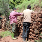 Personas reparando un trozo de pared de piedra seca en la ruta del Quinto Lago.