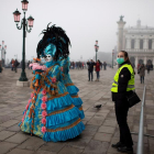 Gent disfressada ahir al Carnaval de Venècia, a prop de la plaça San Marco, al costat d’una guàrdia de seguretat amb màscara.