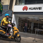Un repartidor monta en motocicleta frente a una tienda de Huawei, ayer lunes en Pekín.