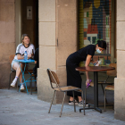 Una cambrera desinfecta les taules i les cadires en un bar de Barcelona.
