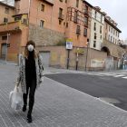 Una mujer caminando ayer por el centro de León con mascarilla y una bolsa de la compra.
