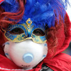 Una persona con la máscara de Carnaval y una mascarilla de papel por el coronavirus.