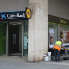 Operarios cambiando el logo de Bankia por el de Caixabank.