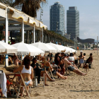 Varias personas disfrutan de un chiringuito este sábado en la playa de la Barceloneta, en Barcelona.