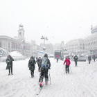Diverses persones caminen per la Puerta del Sol coberta de neu.