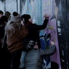 Un grup de joves pinta un mural en un carrer de Belfast.