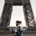 Una dona passeja amb mascareta davant de la Torre Eiffel.