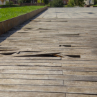 Imatge del paviment de fusta del cobriment de les vies, amb moltes làmines aixecades.