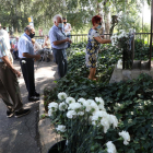 Vecinos depositando claveles blancos en el monumento de Butsènit que recuerda la tragedia.