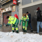 Dos operaris treballen en la retirada de la neu i el gel del carrer.