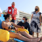 El president Aragonés parla amb una de les usuàries del servei de bany adaptat de Creu Roja a la platja de Caldes d’Estrac.