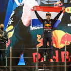 Max Verstappen festeja en el podio su primer título mundial de Fórmula Uno, con Lewis Hamilton a su lado aplaudiendo.
