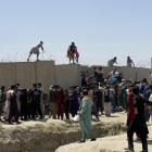 Decenas de afganos intentan entrar a las pistas del aeropuerto de Kabul saltando las alambradas.