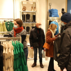 Varias personas miran ropa en el interior de una tienda del Eix Comercial.