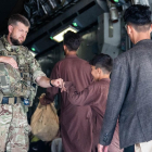 Un militar británico saluda a un menor afgano a punto de embarcar en un avión que le sacará de Kabul.