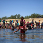 Un migrante haitiano carga a una niña mientras cruza a pie el Río Grande, que separa México y EEUU.